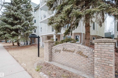 The property features a brick sign with embossed lettering, surrounded by mature evergreen trees