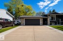 Contemporary exterior featuring a stone facade, a dark garage door, and ample concrete driveway