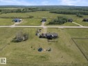 Expansive rural property featuring a two-story residence with a multi-level deck, surrounding green space, and a gravel driveway