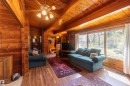 Inviting living area featuring wood-finish flooring, vaulted wood plank ceilings with exposed beams, and a ceiling fan with integrated lighting