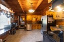 Kitchen featuring wood plank walls and ceiling, exposed wood beams, stainless steel appliances, a pot rack, and a built-in countertop extension