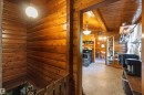 Wood-paneled interior featuring a kitchen with light wood cabinetry, stainless steel appliances, and a hanging pendant light fixture