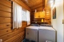 Laundry area featuring wood-paneled walls and ceiling, a window, a wall-mounted shelf, and wood cabinetry