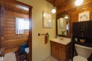 Bathroom featuring a wood vanity with integrated sink, an ornate wood-framed mirror, and wood plank ceiling and wall accents