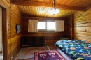 Room featuring wood-paneled walls and ceiling, exposed wood ceiling beam, and a central ceiling light fixture