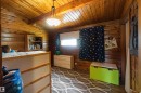 Wood-paneled room featuring a sloped wood-finish ceiling, a built-in bookshelf, a window with a roller shade, and an overhead light fixture