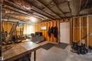 Unfinished basement space featuring exposed wood framing, concrete flooring, and an accessible electrical panel
