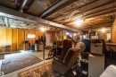 Unfinished basement space featuring exposed wood joists and structural beams, partial wood framing, and a small window