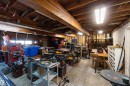 Spacious garage with exposed wood beam ceiling, concrete flooring, fluorescent lighting, and a roll-up door with windows