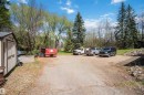 Gravel driveway and parking area featuring a detached storage shed and mature trees