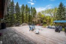 Spacious wood deck with perimeter railing and mature tree backdrop