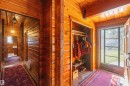 Wood-paneled entryway featuring a solid wood door with a glass insert, exposed wood ceiling beams, and a built-in storage area