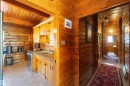 Warm wood-paneled interior featuring a kitchen area with built-in cabinetry, dual basin stainless steel sink, and light-toned flooring