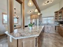 Kitchen island featuring a granite-finish countertop, wood-finish cabinetry, and pendant lighting