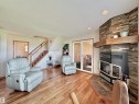 Living area featuring a stone-clad fireplace with a wood mantel, wood-finish flooring, and a sliding glass door