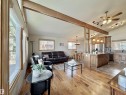 Expansive open-concept living area featuring vaulted ceilings, wood-finish flooring, abundant natural light from large windows, a spacious kitchen island with pendant lighting, and stainless steel appliances