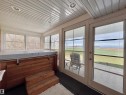 Sunroom featuring a built-in hot tub with wooden surround, full-length windows, recessed lighting, white paneled ceiling, and glass-paneled patio doors opening to an outdoor area