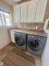 Dedicated laundry area featuring a countertop with an integrated sink, upper white cabinetry, and a window