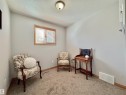 Neutral wall color with textured ceiling, wood-trimmed window with blinds, and light brown carpeting
