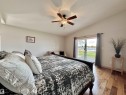Vaulted ceilings accent a spacious room featuring wood-finish flooring and a ceiling fan with integrated lighting