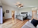 Vaulted ceiling bedroom featuring hardwood flooring, a ceiling fan with integrated lighting, and a wood-finish bed frame