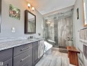 Walk-in shower with glass enclosure, large format wall tiles, and pebble tile accent
