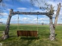 Expansive green lawn with a custom wooden swing structure featuring a bench swing
