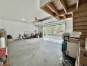 Spacious garage featuring a concrete floor, white painted walls, exposed ceiling joists, and an automatic overhead garage door