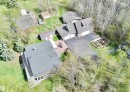 Expansive property featuring multiple structures, mature trees, a defined garden area, paved driveways, and brick patio