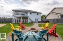 Expansive backyard featuring a circular paver patio with fire pit, surrounding lawn, and a multi-level deck with white railing
