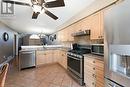 Kitchen with ceiling fan with notable chandelier, sink, vaulted ceiling, appliances with stainless steel finishes, and light tile patterned flooring