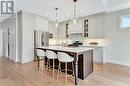 Kitchen with appliances with stainless steel finishes, decorative light fixtures, tasteful backsplash, sink, and a kitchen island with sink