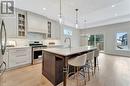 Kitchen featuring sink, premium range hood, a kitchen island with sink, hanging light fixtures, and stainless steel appliances