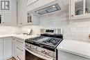 Kitchen featuring light stone counters, white cabinets, stainless steel range with gas cooktop, and wall chimney exhaust hood