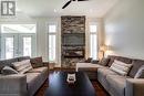 Living area with a ceiling fan, a fireplace, dark wood-style flooring, and vaulted ceiling