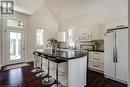 Kitchen with freestanding refrigerator, white microwave, dark countertops, a kitchen bar, and high vaulted ceiling