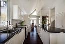 Kitchen featuring white appliances, dark countertops, a sink, white cabinetry, and lofted ceiling