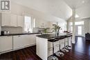 Kitchen featuring white appliances, a sink, dark countertops, dark wood-type flooring, and lofted ceiling