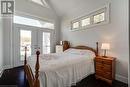 Bedroom with vaulted ceiling, access to outside, baseboards, dark wood finished floors, and french doors