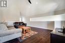 Living room with lofted ceiling, dark wood-type flooring, and baseboards