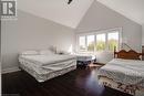 Bedroom featuring baseboards, high vaulted ceiling, and wood finished floors