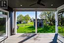 Wooden terrace featuring ceiling fan, an outdoor structure, a lawn, and a storage shed