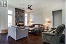 Living room featuring a ceiling fan, healthy amount of natural light, dark wood-style flooring, a stone fireplace, and recessed lighting