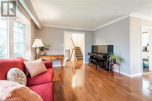 Living room featuring wood finished floors, baseboards, ornamental molding, and stairway