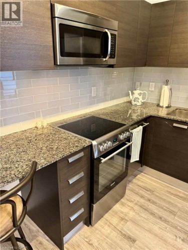 Kitchen with modern cabinets, stainless steel appliances, light stone countertops, backsplash, and light vinyl flooring