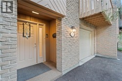 Entrance to property with asphalt driveway, brick siding, and a garage