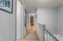 Hallway featuring an upstairs landing, a textured ceiling, and light wood finished floors