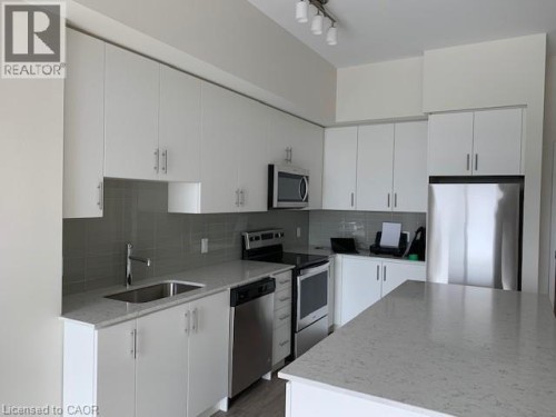 Kitchen featuring stainless steel appliances, white cabinets, and light stone counters
