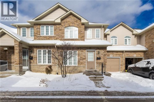 View of front facade featuring a garage and stone siding