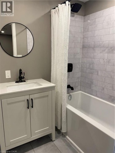 Bathroom with shower / bathtub combination with curtain, vanity, and light tile patterned floors